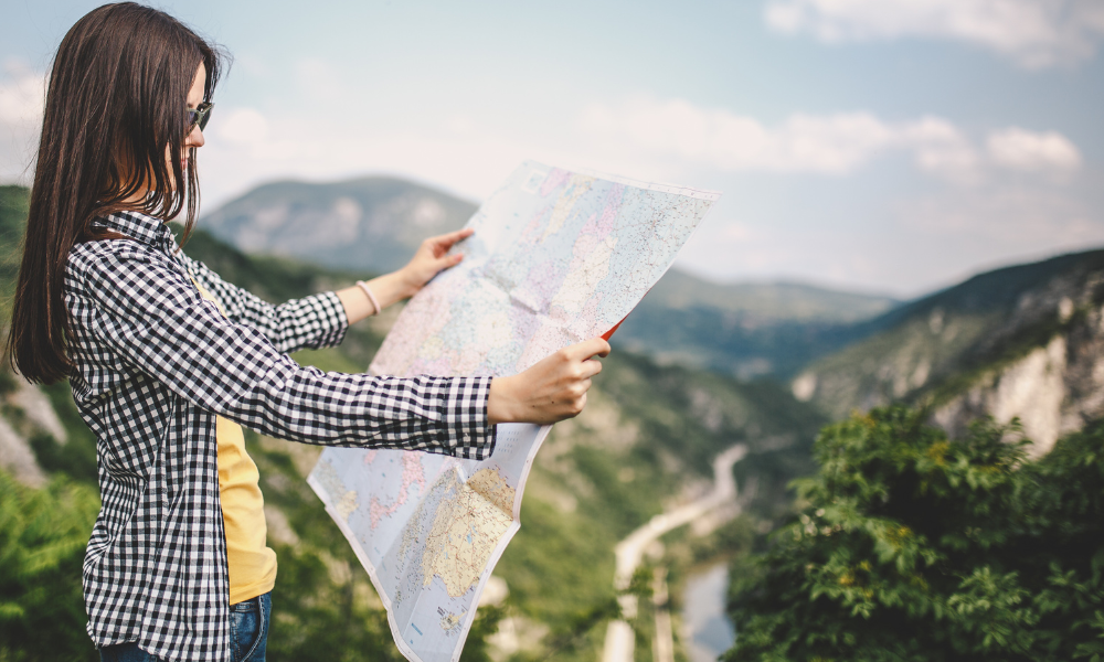 Girl holding map with mountainous scenic background