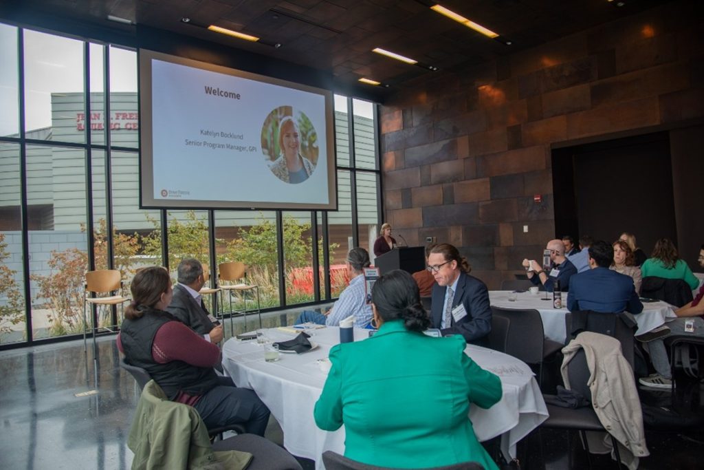 A group of people is listening to an introduction slide.