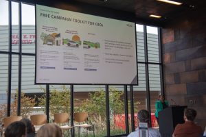 A group of people view a presentation slide about an electric vehicle education toolkit.